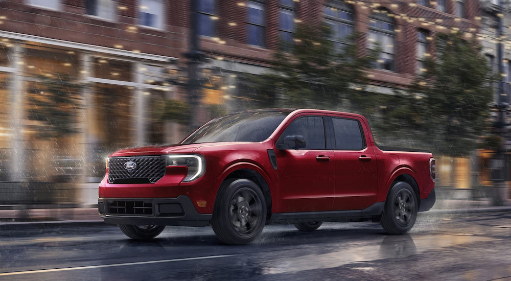 A red 2025 Ford Maverick driving on a rainy city street.