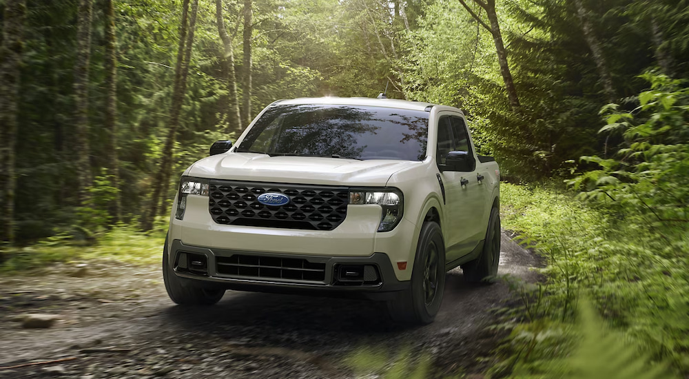 A white 2025 Ford Maverick XLT driving through the woods.