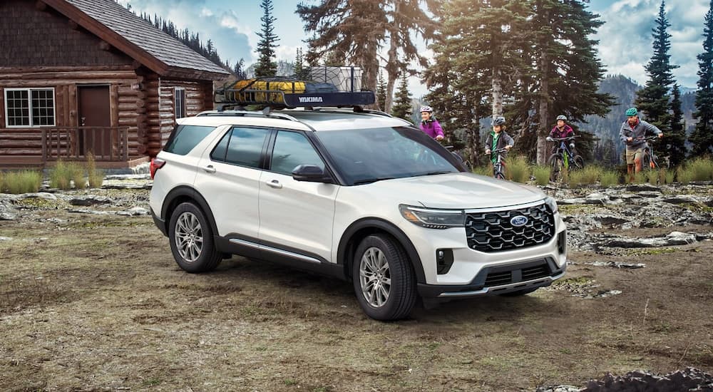 A white 2025 Ford Explorer parked by a cabin and angled right.