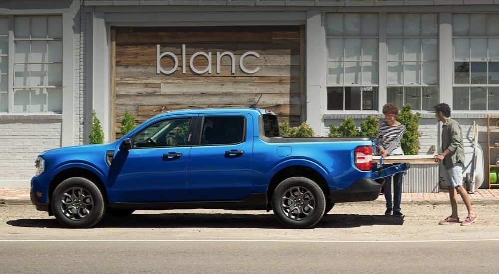 Side angle view of a blue 2024 Ford Maverick XLT parked by a building.