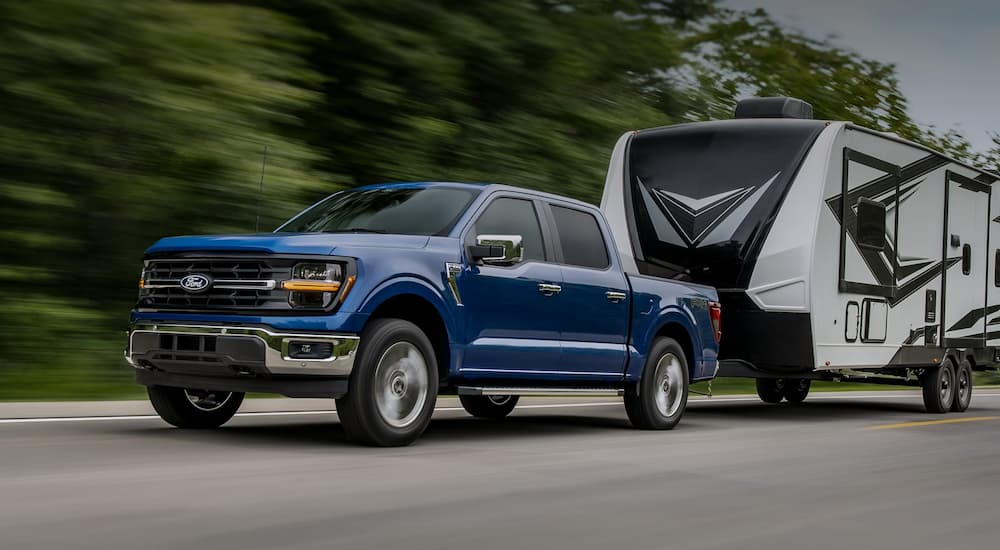A blue 2025 Ford F-150 towing a camper from a Ford dealer near Metamora.