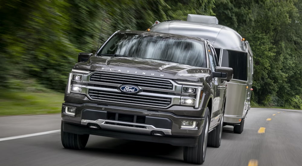 Front angle view of a black 2025 Ford F-150 Platinum Plus towing a camper.