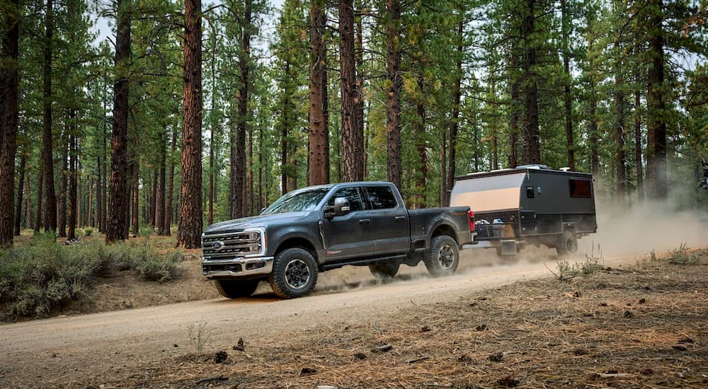 A grey 2025 Ford F-250 Tremor is shown from the side while towing a camper.