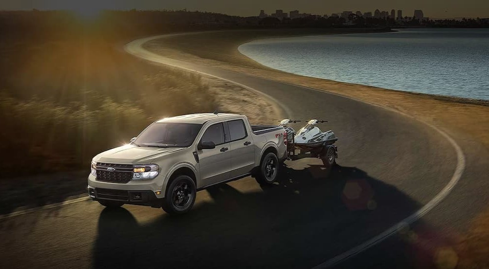 A silver 2024 Ford Maverick towing a trailer after viewing used cars for sale near Metamora.