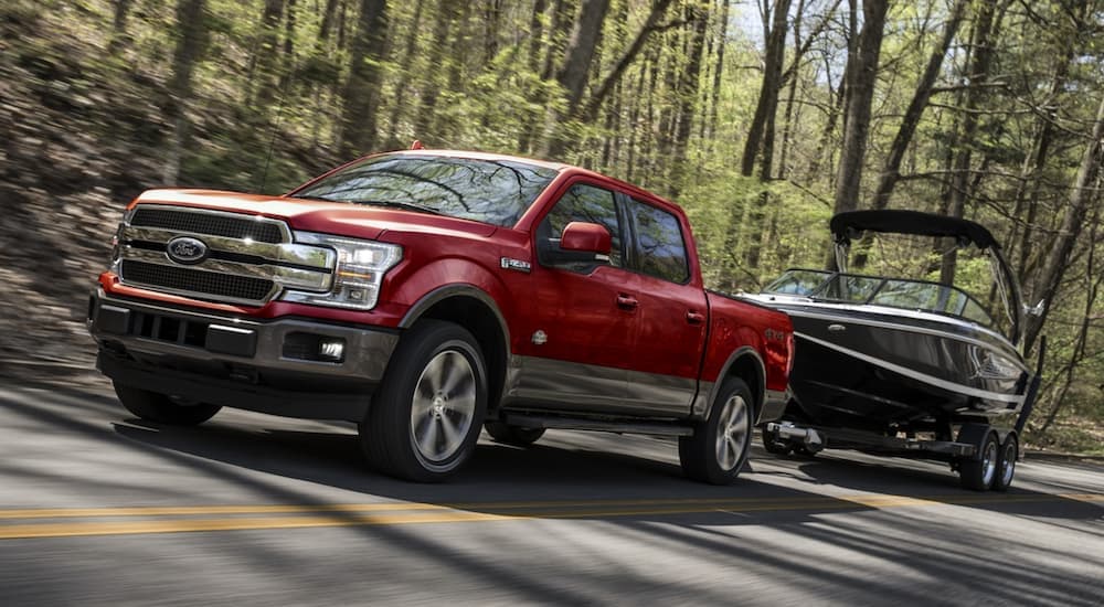 A red 2020 Ford F-150 towing a boat.