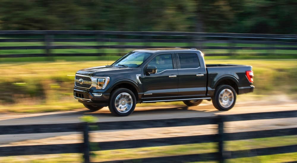 A black 2021 Ford F-150 driving near a fence.