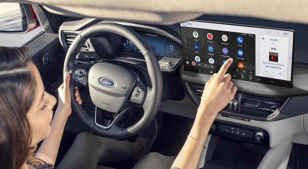 A woman using the infotainment display on a 2025 Ford Escape