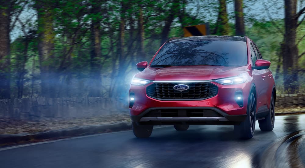 A red 2025 Ford Escape driving down a wet road