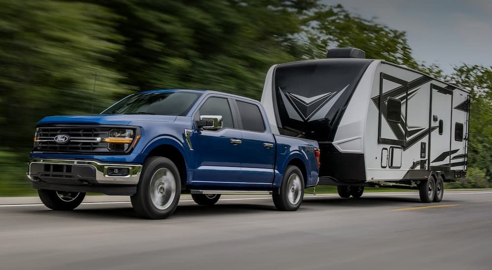 A blue 2025 Ford F-150 towing a camper.