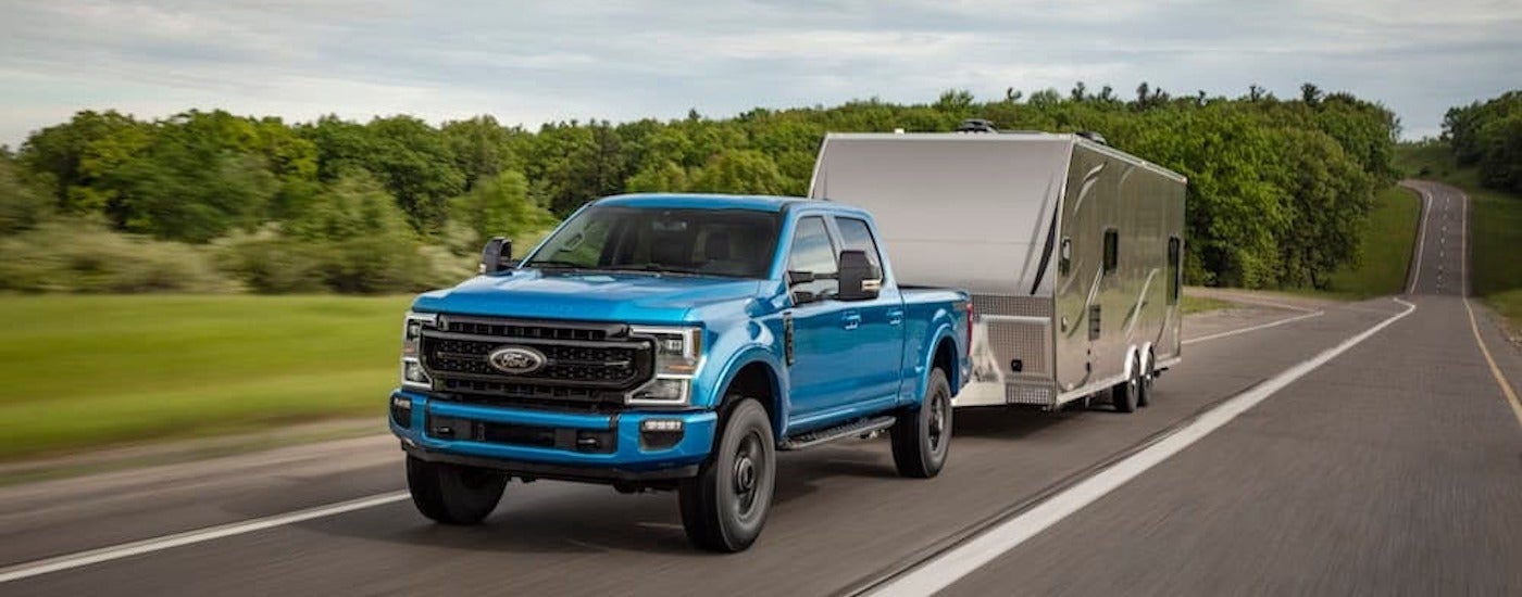 A blue 2020 Ford F-250 Super Duty is shown from the front at an angle while towing a trailer.