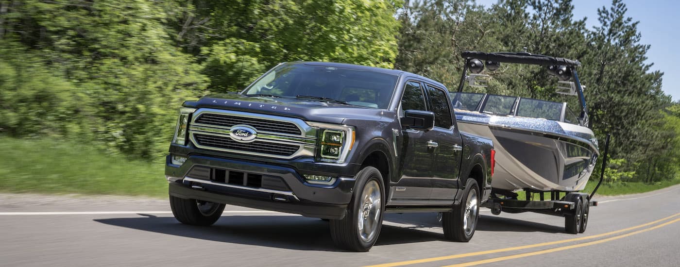 A grey 2022 Ford F-150 Limited is shown from the front at an angle while towing a boat.