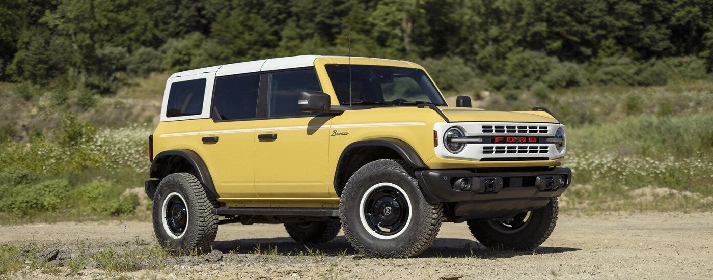 A yellow 2024 Ford Bronco Heritage Limited Edition parked off-road at a Ford dealer near El Paso.
