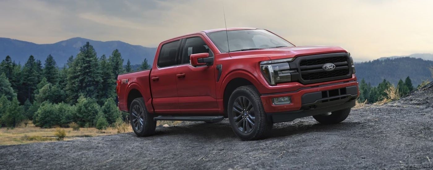 A red 2024 Ford F-150 Lariat parked off-road and angled right.