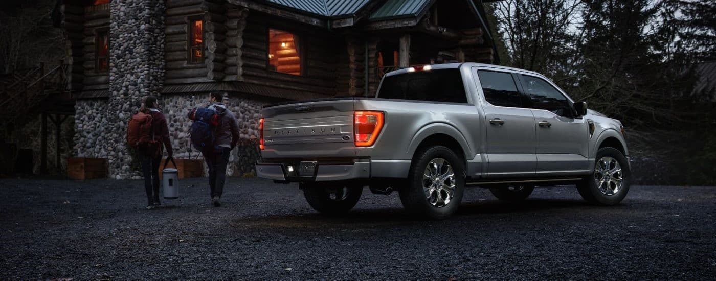 A silver 2023 Ford F-150 Platinum parked outside a cabin.