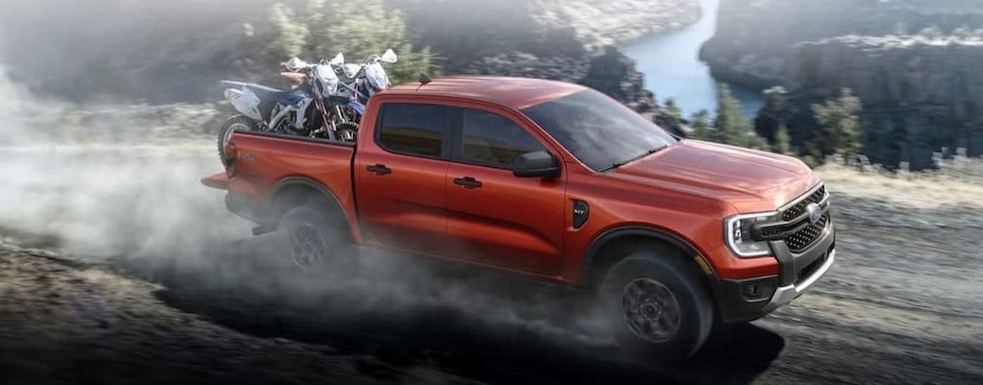 A red 2024 Ford Ranger driving on a dirt road.