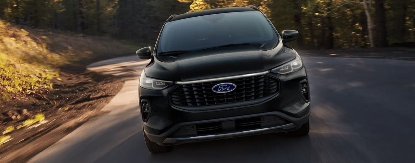 A black 2024 Ford Escape driving down a road